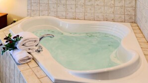A rectangular hot tub with a greenish water color, a white towel, and a bouquet of flowers on the side.