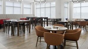 A modern dining area with multiple tables and chairs, large windows, and ceiling lights. - Hilton Garden Inn Indianapolis Northeast/Fishers (Fishers)
