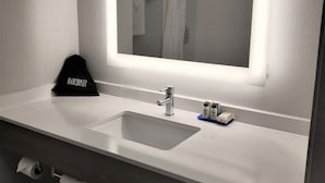 Un baño con un espejo grande, un lavamanos y un perchero para toallas.