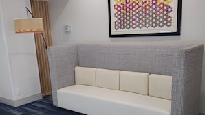 Una habitación moderna con un sofá estampado, una alfombra azul y una obra de arte geométrica en la pared.