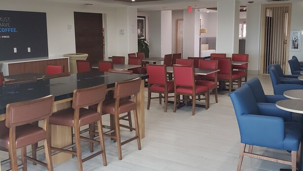 A spacious indoor area with multiple seating arrangements, including tables and chairs, and a large blackboard on the wall. - Holiday Inn Express & Suites San Antonio-West-SeaWorld Area by IHG (San Antonio)