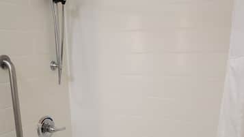 A bathroom with a bathtub, a shower with a handheld showerhead, and a grab bar.