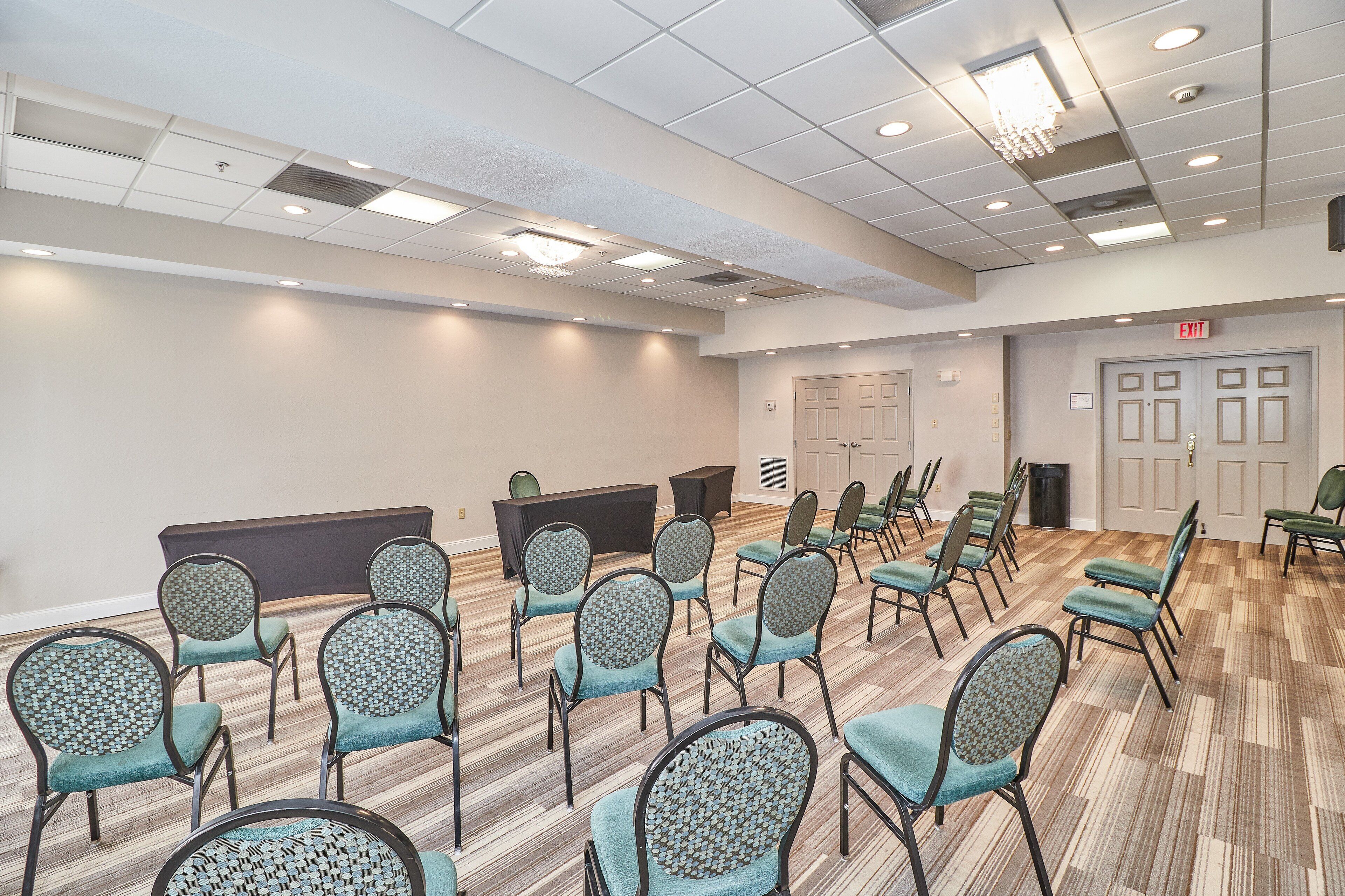 A conference room with rows of chairs, a podium, and a door marked "EXIT".