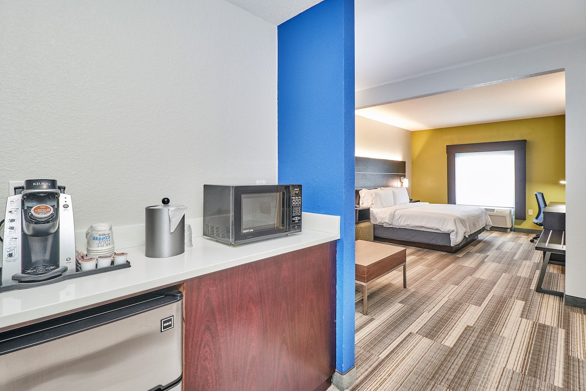 A hotel room with a kitchenette, a bed, a window, and a view of the outside.