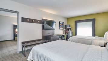 A hotel room with two beds, a desk with a computer, a TV, and a coffee machine.