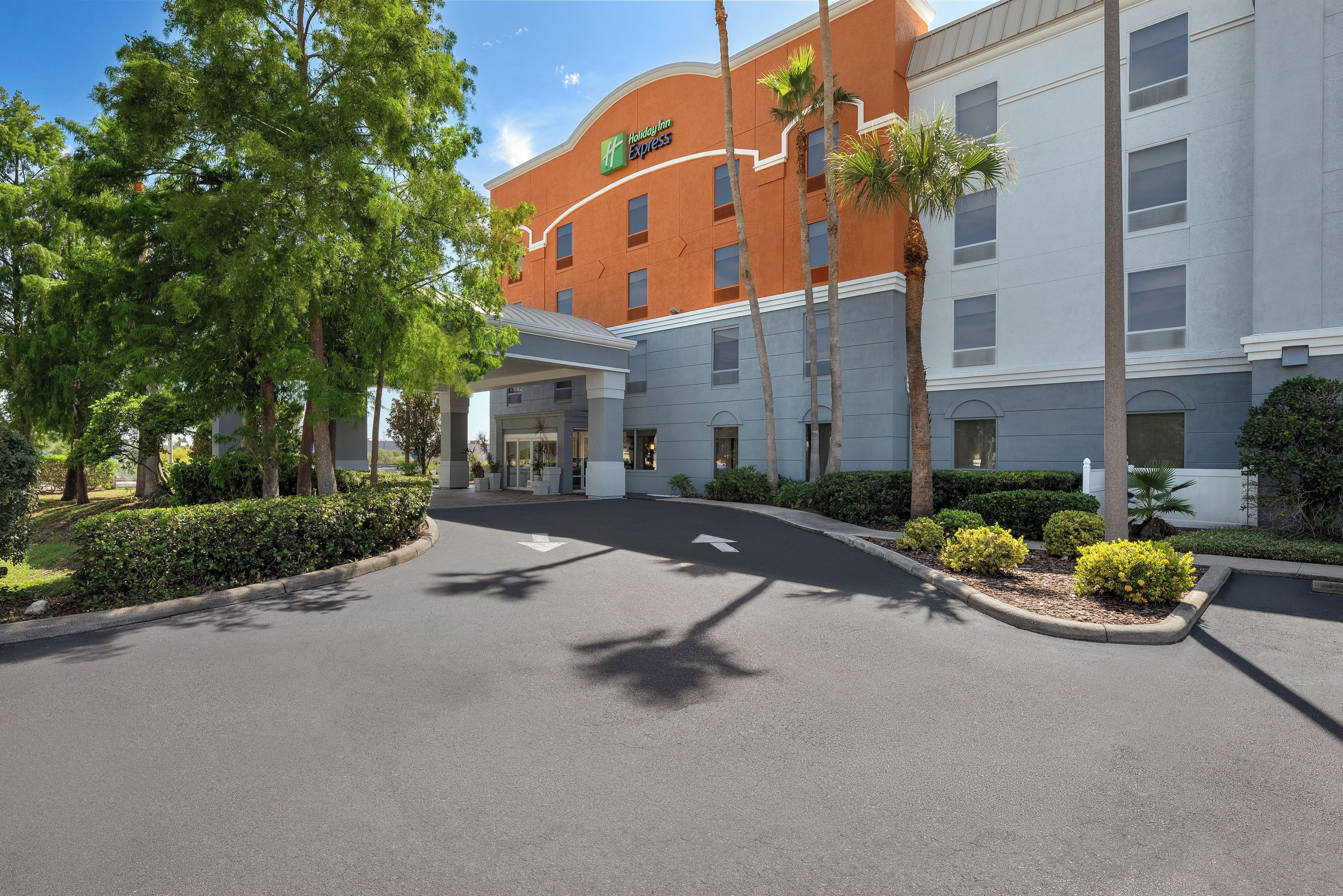 A Holiday Inn Express building with a curved facade, a covered entrance, and a landscaped driveway.