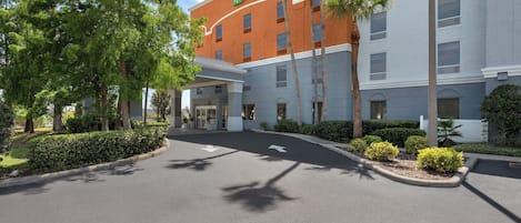 A Holiday Inn Express building with a curved facade, a covered entrance, and a landscaped driveway.