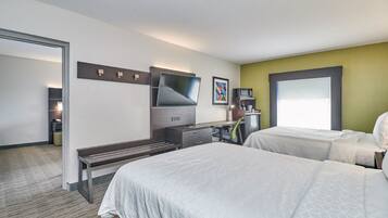 A hotel room with two beds, a desk, a television, and a coffee machine.