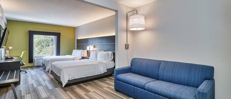 A hotel room with a bed, a desk, a chair, a sofa, and a window.