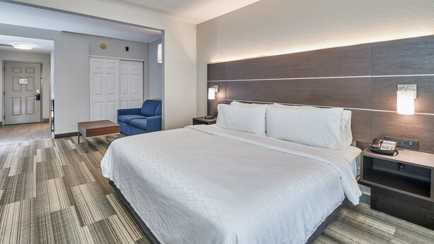 A hotel room with a large bed, a desk with a phone, a chair, and a wall-mounted light. - Holiday Inn Express Hotel & Suites Clearwater/Us 19 N by IHG (Clearwater)