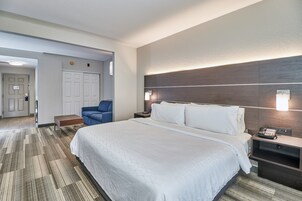A hotel room with a large bed, a desk with a phone, a chair, and a wall-mounted light.
