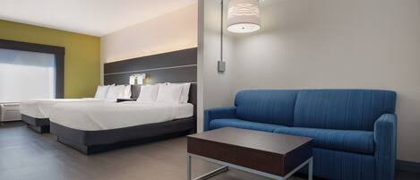 Ett modernt hotellrum med en säng, en soffa, ett litet bord och en väggmonterad lampa.
