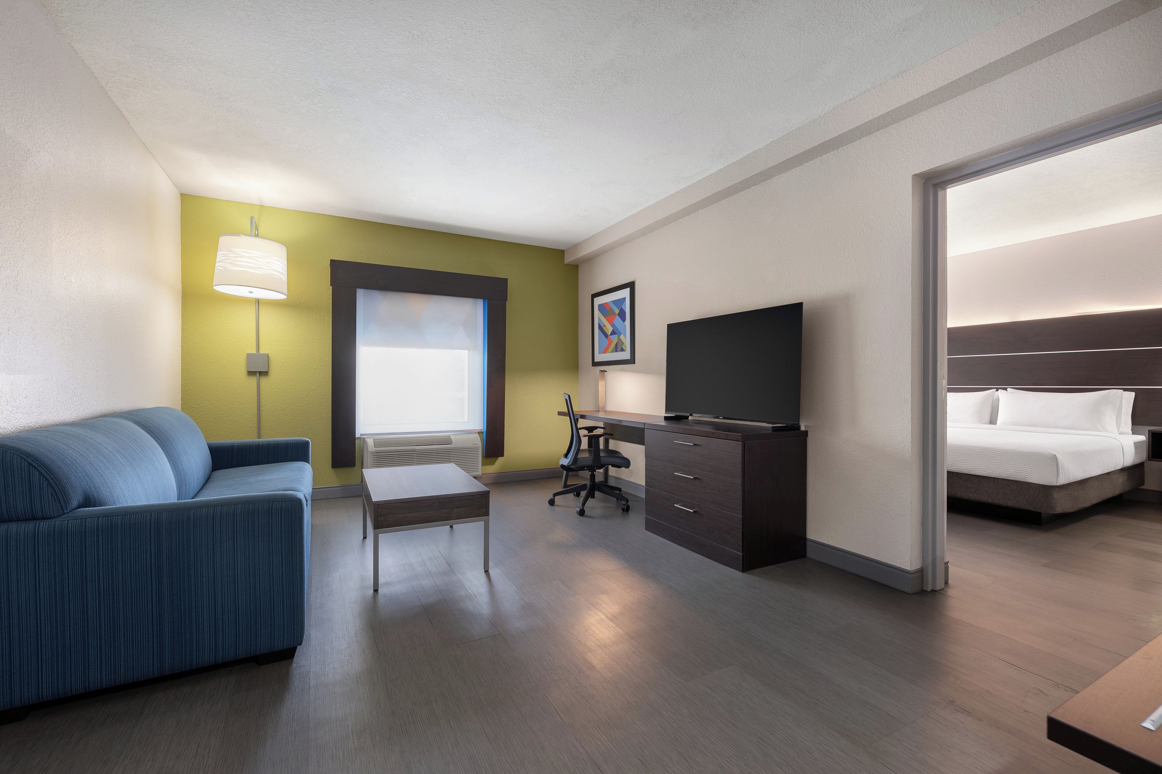 Ein Hotelzimmer mit einem Bett, einem Schreibtisch mit Stuhl, einer Couch und einem Fernseher.