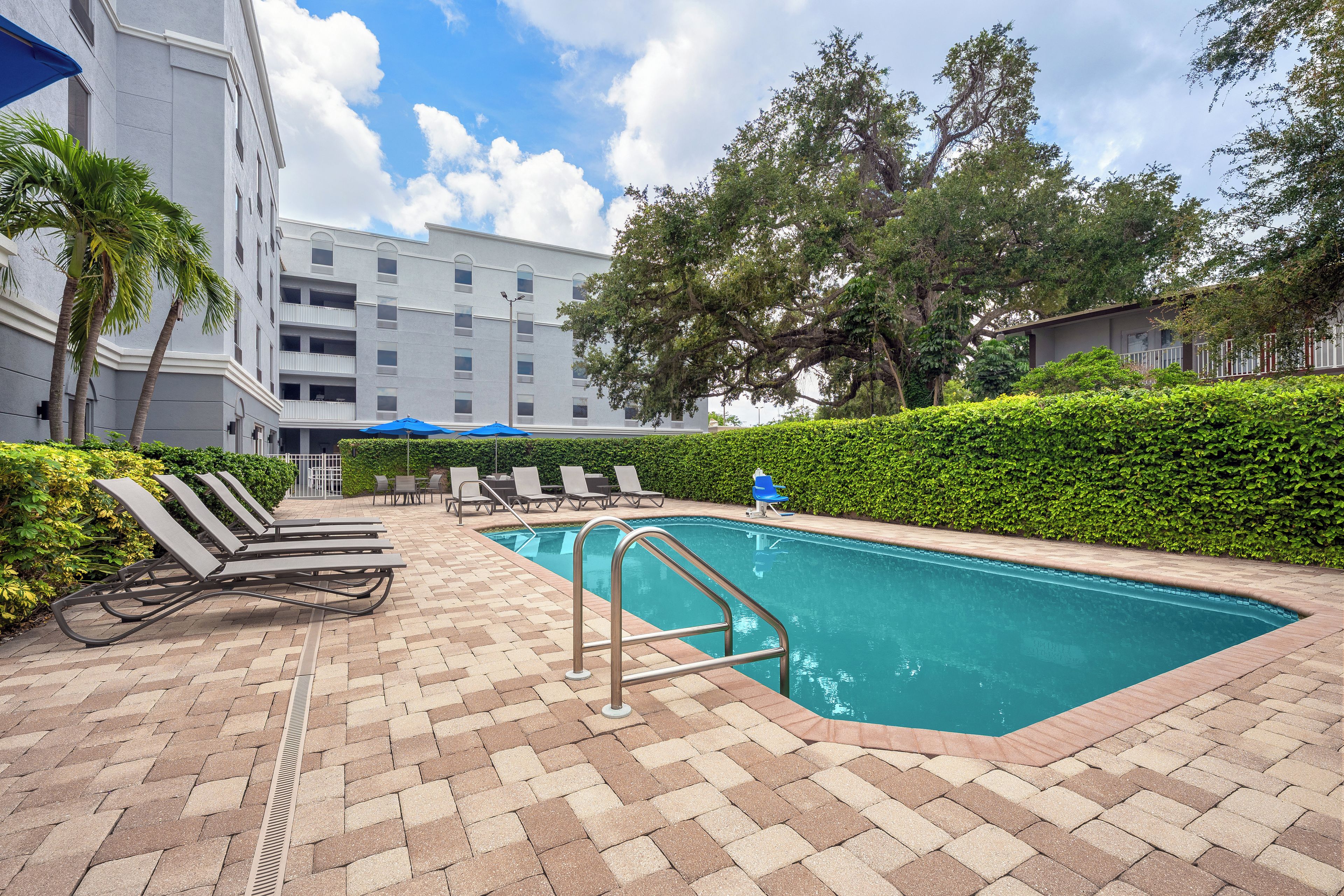 A swimming pool area with lounge chairs and a building in the background.