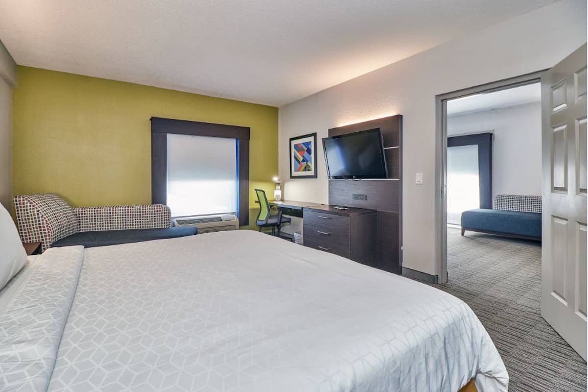 A hotel room with a large bed, a desk, a TV, and a window.