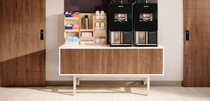 Zona de cafè amb dues màquines de cafè, un molinillo i diversos articles relacionats amb el cafè exposats a prestatgeries.