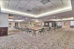 A conference room with a large table and chairs, carpeted floor, and ceiling lights.