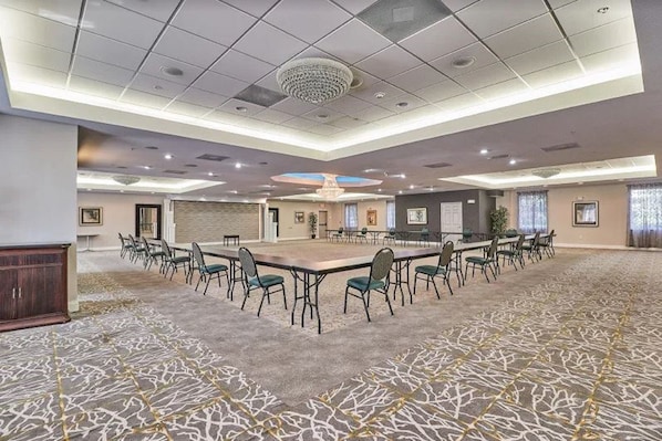 Una sala de conferències amb un gran taulell i cadires, terra amb moqueta i llums al sostre.