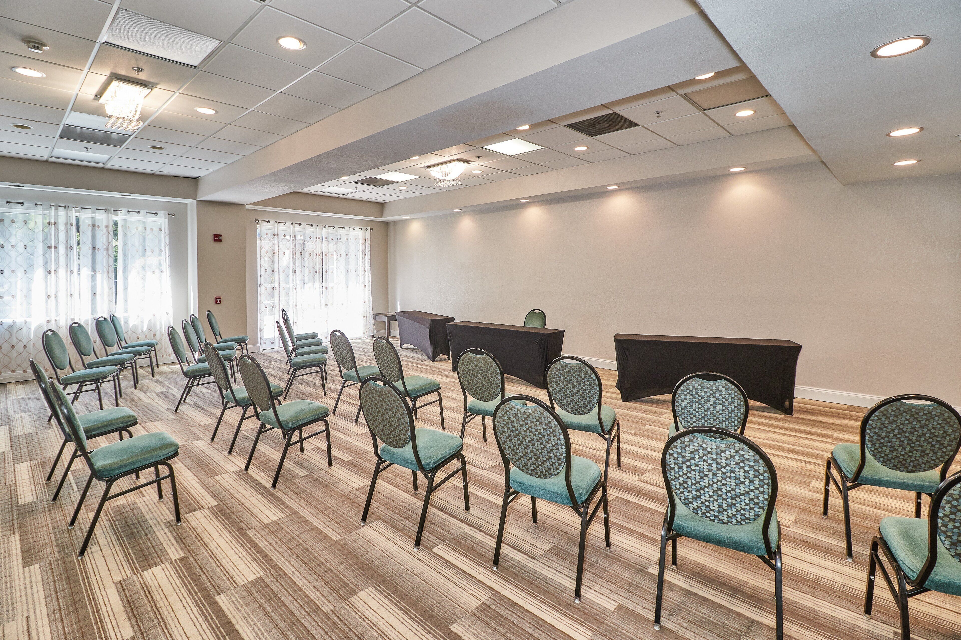 A conference room with rows of chairs, a podium, and a carpeted floor.