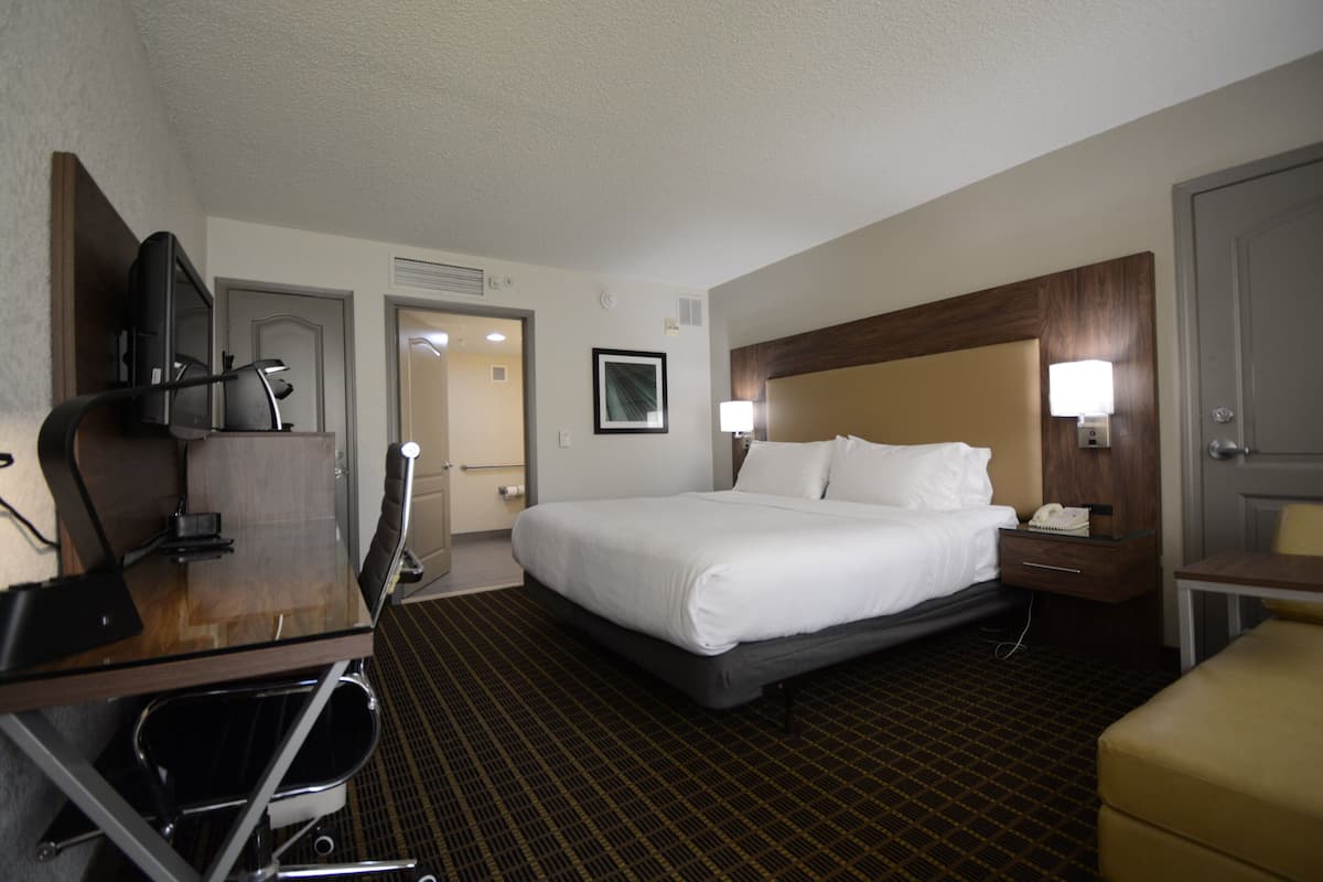 A hotel room with a bed, desk, chair, and a television.