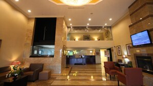 A lobby with a chandelier, seating area, reception desk, and a television. - Holiday Inn Hazlet by IHG (Hazlet)