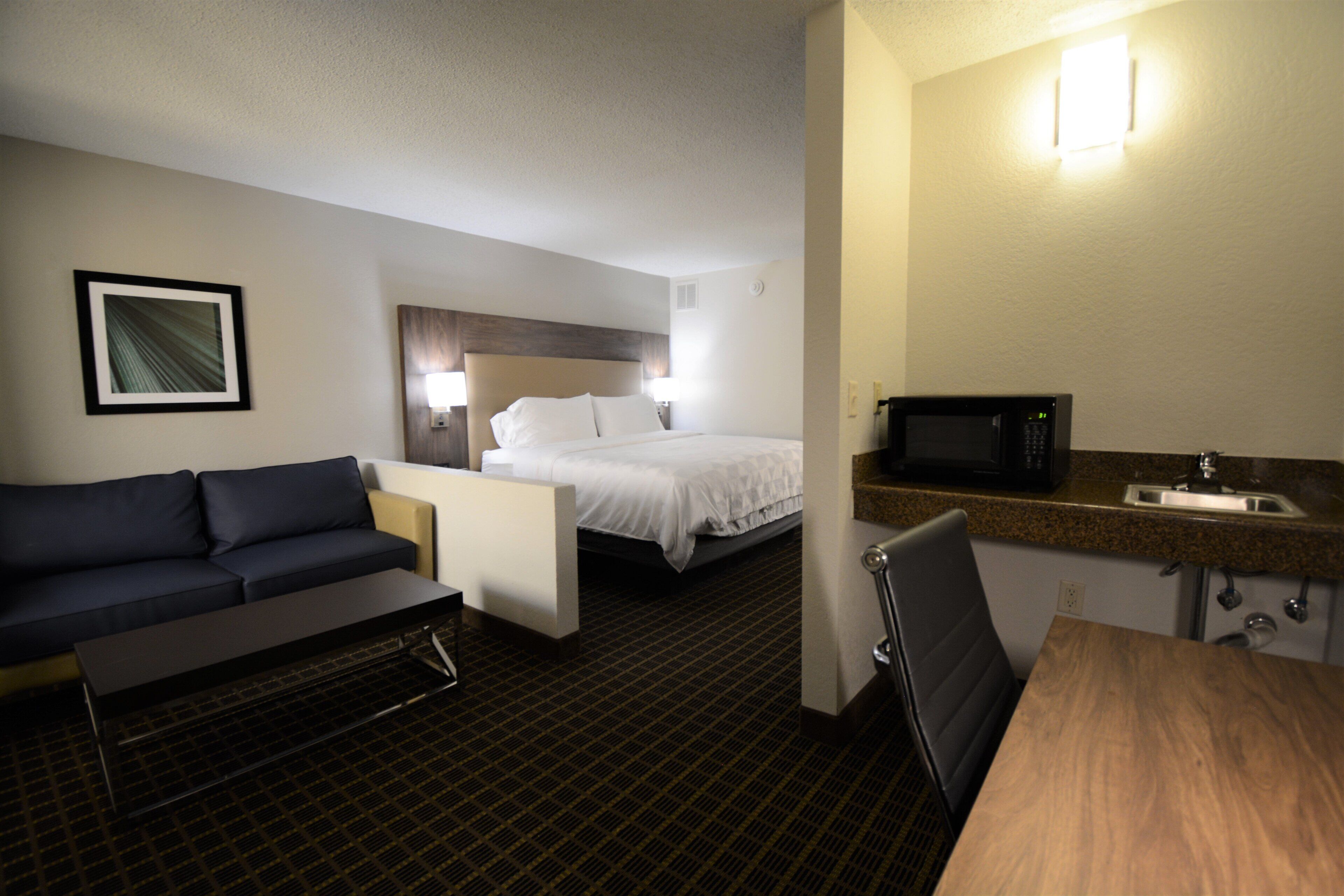 Ein Hotelzimmer mit einem Bett, einer Couch, einem Esstisch, einer Mikrowelle und einem Waschbecken.