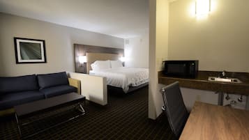 Ein Hotelzimmer mit einem Bett, einer Couch, einem Esstisch, einer Mikrowelle und einem Waschbecken.