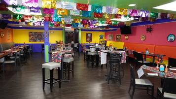 A restaurant with multiple tables and chairs, colorful decorations, and a vibrant interior.