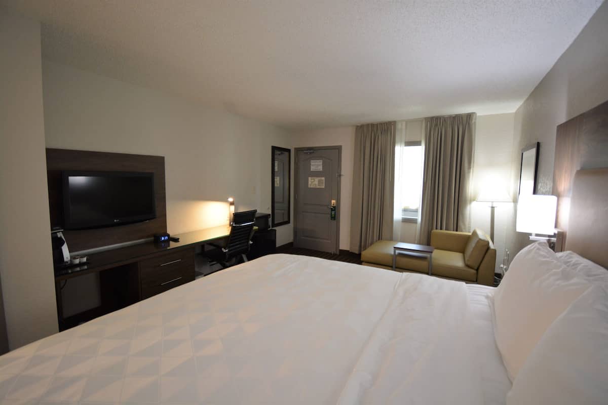 A hotel room with a large bed, a desk with a computer, a television, and a chair.