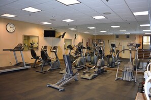A gym with multiple cardio machines, a clock, and a television on the wall. - Holiday Inn Hazlet by IHG (Hazlet)