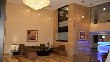 A lobby with seating, a chandelier, and a reception desk.