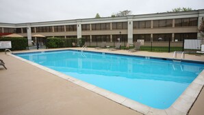A rectangular pool with a tiled edge, surrounded by lounge chairs and a fence. - Holiday Inn Hazlet by IHG (Hazlet)