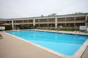 A rectangular pool with a tiled edge, surrounded by lounge chairs and a fence. - Holiday Inn Hazlet by IHG (Hazlet)