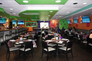 A restaurant with multiple tables and chairs, a bar area, and several televisions on the walls. - Holiday Inn Hazlet by IHG (Hazlet)