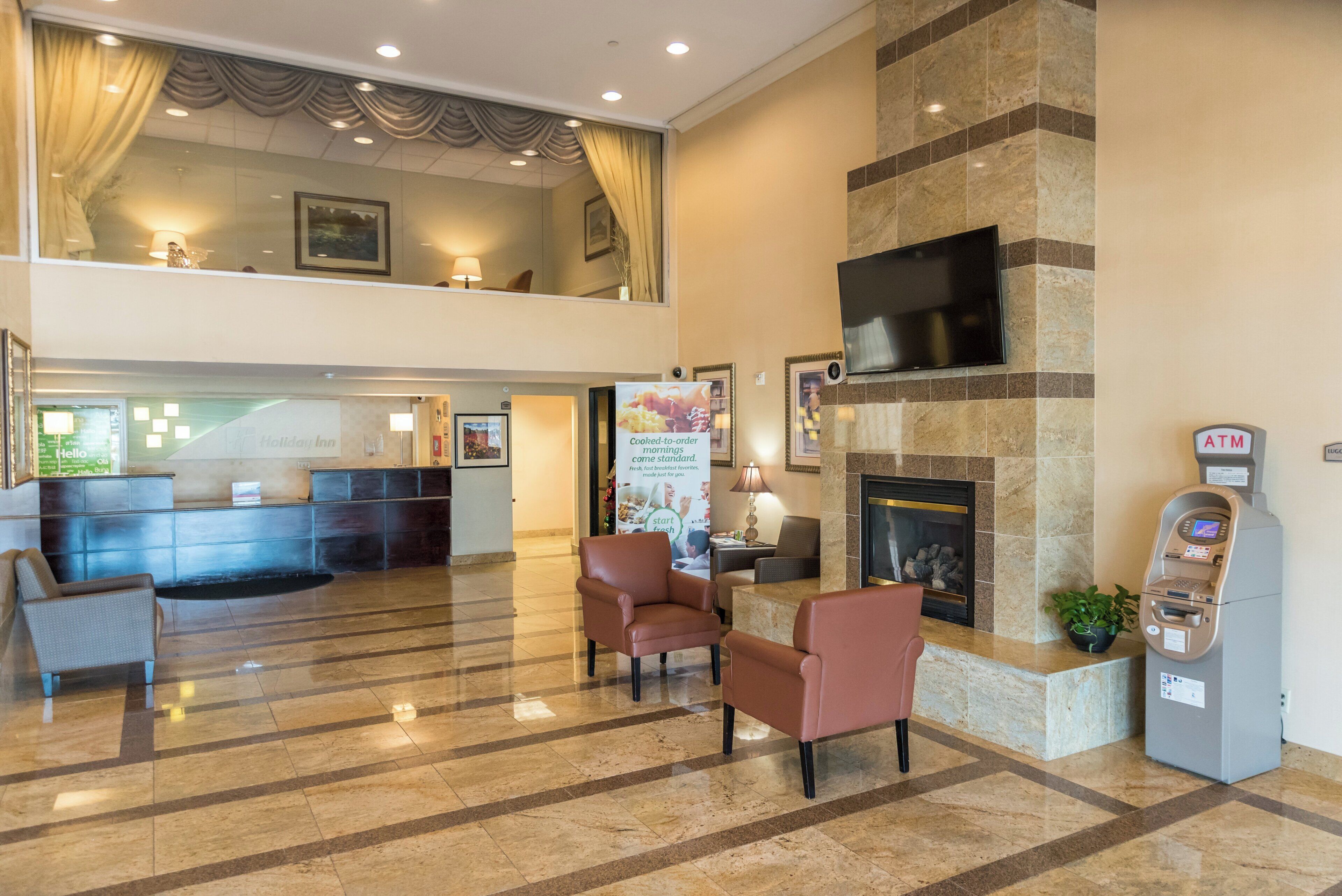 A hotel lobby with a reception desk, seating area, fireplace, and ATM.