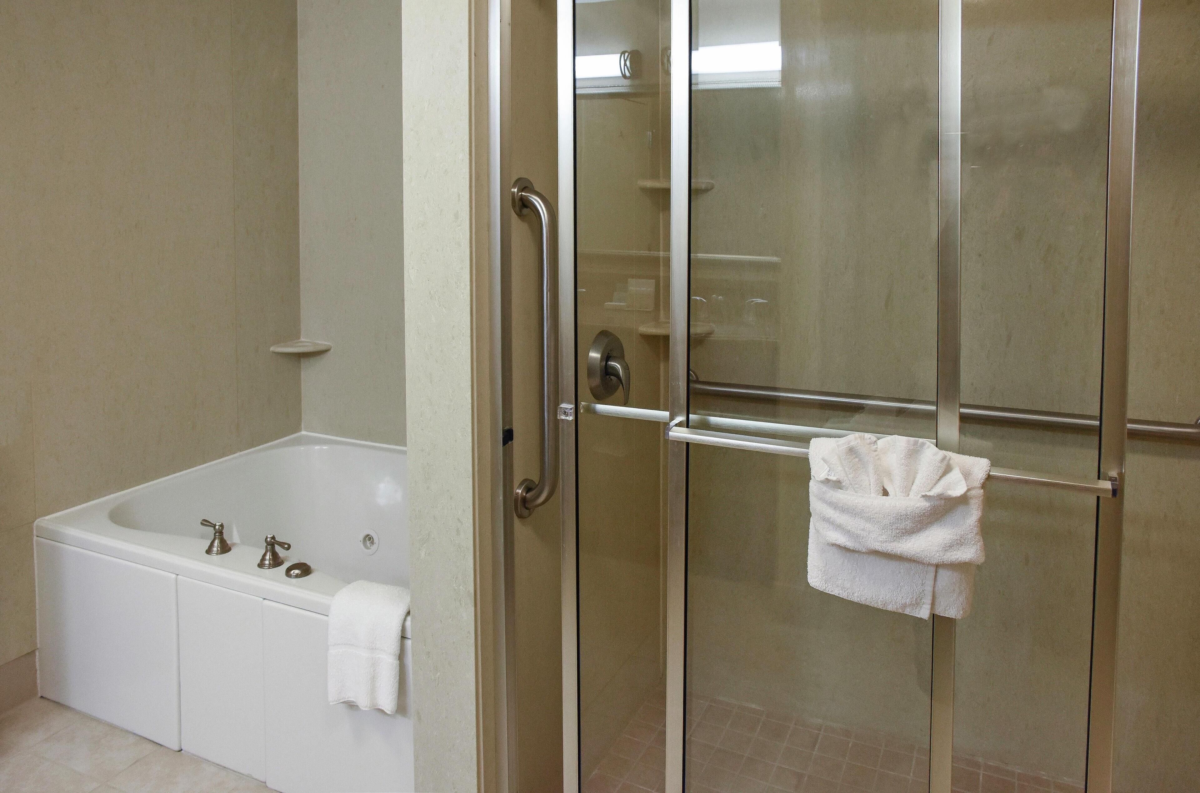 Un baño con ducha de vidrio, una bañera blanca y una toalla colgada en el pomo de la puerta de la ducha.