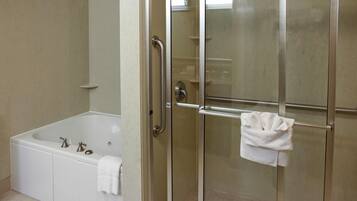 Un baño con ducha de vidrio, una bañera blanca y una toalla colgada en el pomo de la puerta de la ducha.