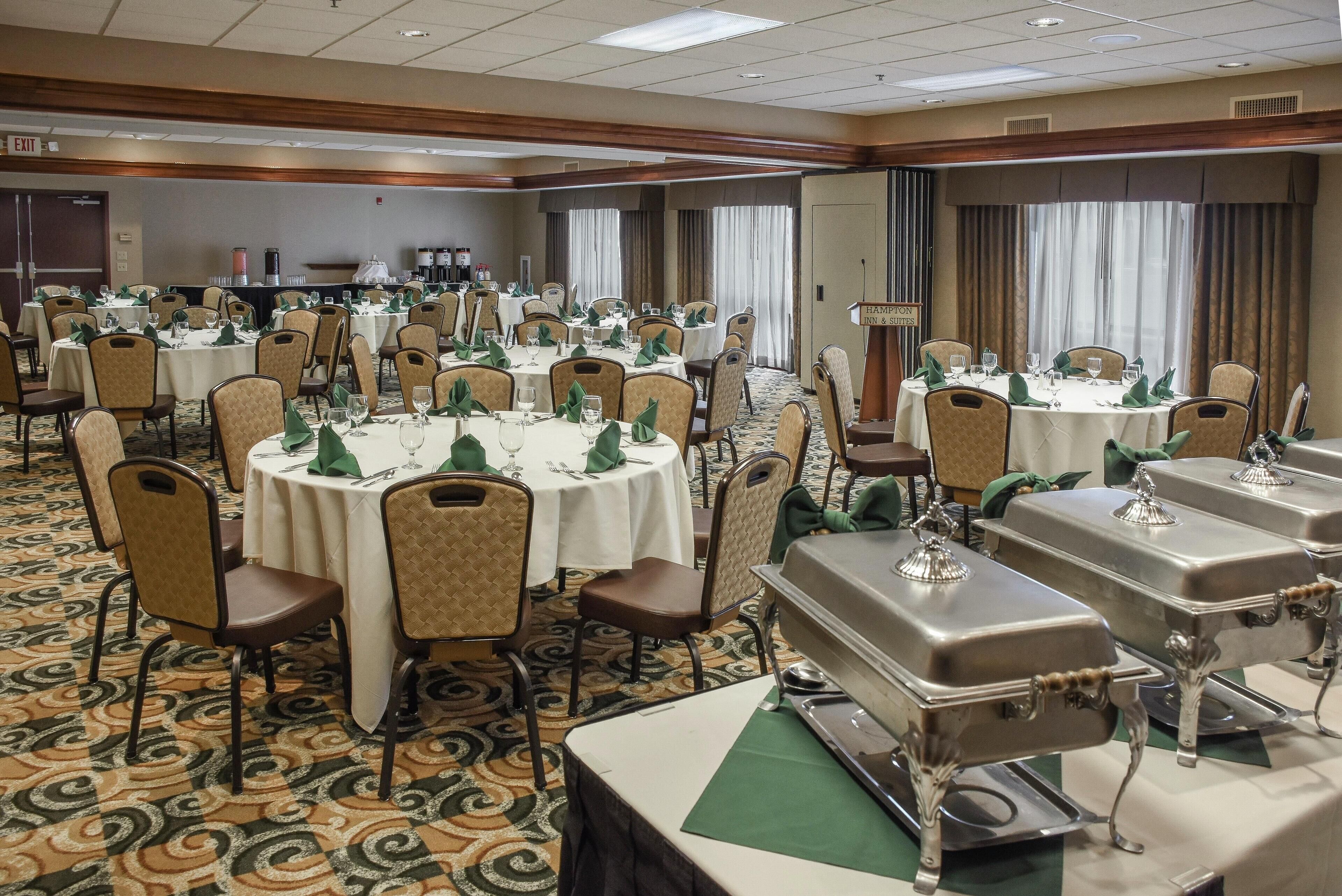 Un salón de banquetes con mesas redondas, sillas y estaciones de buffet.