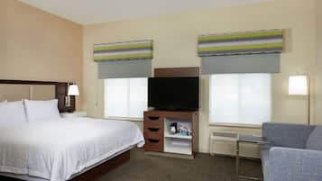 A hotel room with a bed, a television, a coffee maker, and a chair.