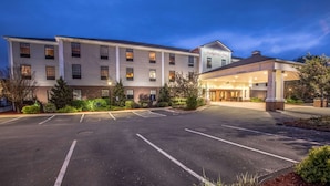 Ein großes, mehrgeschossiges Hotel mit überdachter Eingangsparte und Parkplatz.