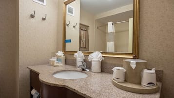 A bathroom with a granite countertop, a sink, a mirror, and toiletries.