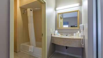 A bathroom with a shower, a sink, a mirror, and a telephone.