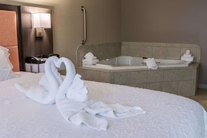 A hotel room with a large bed, a bathtub, a telephone, and a wall-mounted lamp.