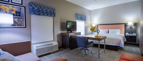 A hotel room with a bed, desk, chair, and a television.