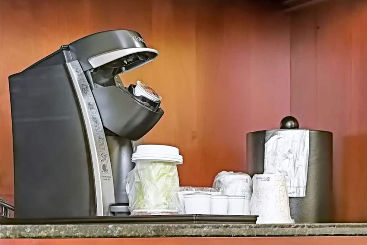 A coffee machine with a drip tray, a coffee pot, and a paper towel dispenser on a countertop.