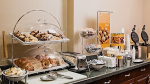 A breakfast buffet with various pastries, bread, and waffles. - Hampton Inn Littleton (Littleton)