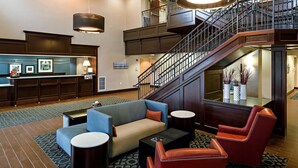 A lobby with a reception desk, seating area with sofas and chairs, a staircase, and a large window. - Hampton Inn Littleton (Littleton)