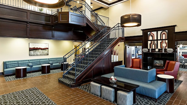 A spacious lobby with a staircase, seating areas, and a fireplace. - Hampton Inn Littleton (Littleton)