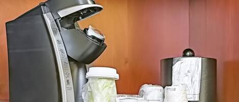 A coffee machine with a drip tray, a milk frother, and a coffee grinder on a countertop.