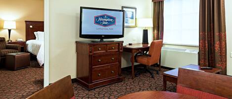 A Hampton Inn Littleton, NH hotel room with a television, a desk, a chair, a bed, and a dining area.